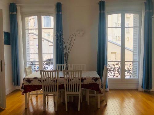 une salle à manger avec une table, des chaises et des fenêtres dans l'établissement Comfortable and Luxury Appart-Center of Paris, à Paris