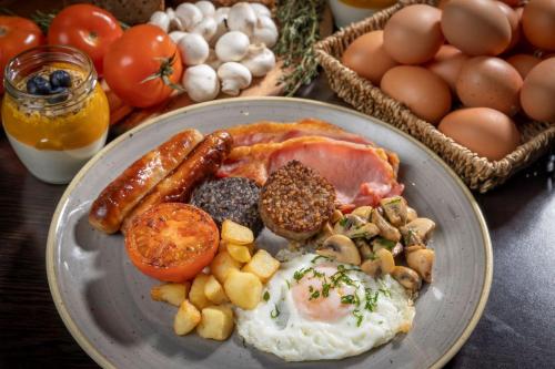 a plate of breakfast food with eggs sausage and tomatoes at Clayton Hotel London Wall in London