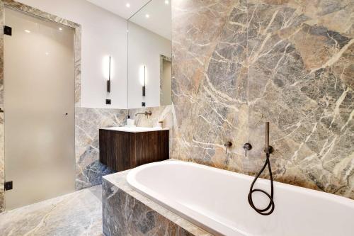 La salle de bains est pourvue d'une grande baignoire et d'un lavabo. dans l'établissement Luxury Apartment - 2BR-4P - GeorgeV-Champs Elysees, à Paris