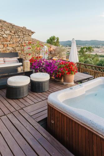 a wooden deck with a hot tub and some flowers at Casa rural con jacuzzi en centro histórico de Pals in Pals