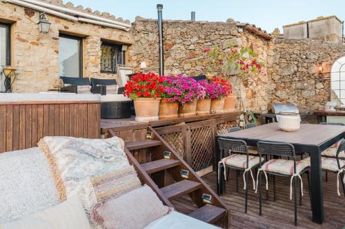 a patio with a table and chairs and flowers at Casa rural con jacuzzi en centro histórico de Pals in Pals