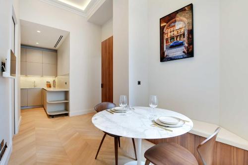 une salle à manger avec une table et des chaises blanches dans l'établissement Luxury apartment with AC - GeorgeV-Champs Elysees, à Paris