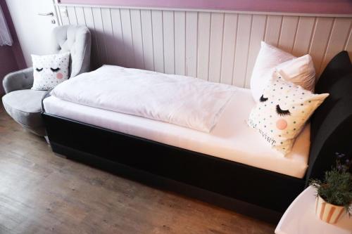 a bed with pillows and a chair in a room at Hotel Wandersleben - Erfurt in Wandersleben