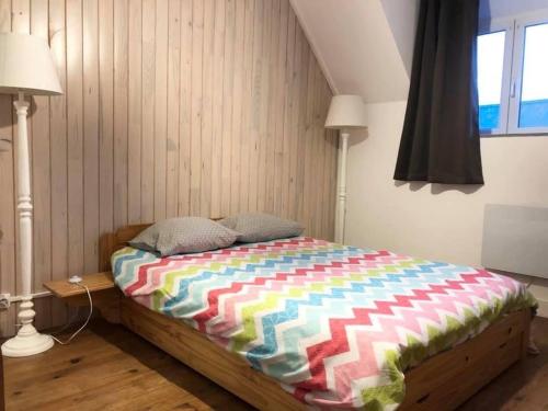 - un lit avec une couette colorée dans une chambre dans l'établissement Gîte 