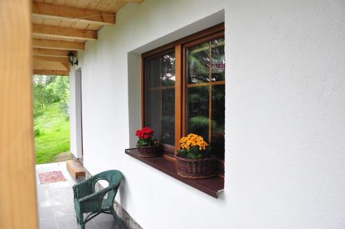 a window with two baskets of flowers on a porch at Chatka Pod Trohańcem in Lutowiska
