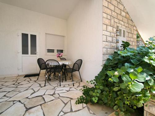 a patio with a table and chairs and a plant at Apartmani Suton in Primošten