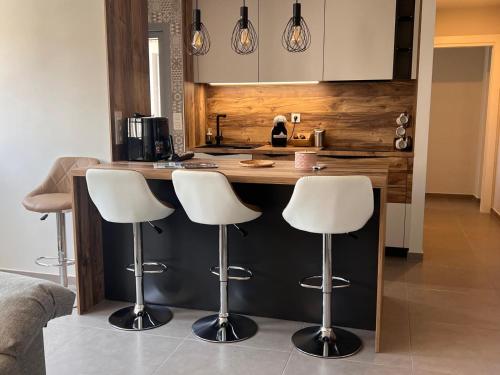 a kitchen with a counter with white bar stools at Rincón de Irene, a 150 mts de Playa del Puerto! in Puerto de Mazarrón