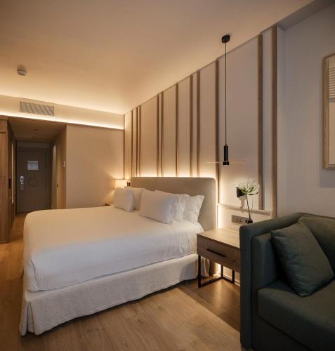a bedroom with a large white bed and a couch at H10 Puerta de Alcalá 4 Sup in Madrid