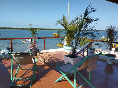 a deck with chairs and plants and a view of the water at Pousada Tycoz Flor do mar in Galinhos