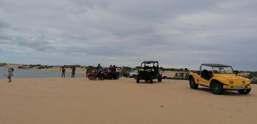 a group of people on the beach with a golf cart at Pousada Tycoz Flor do mar in Galinhos
