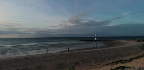 a beach with a lighthouse and the ocean at Pousada Tycoz Flor do mar in Galinhos