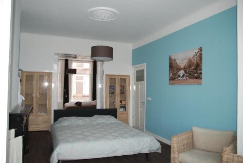 Schlafzimmer mit blauen Wänden, einem Bett und einem Stuhl in der Unterkunft Bed & Breakfast Obrechtstraat in Den Haag