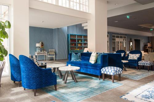 a living room with blue chairs and a blue couch at Grand Hotel Ter Duin in Burgh Haamstede