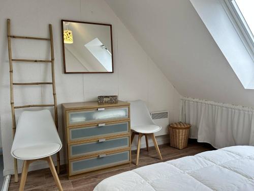 - une chambre avec deux chaises et une commode avec un miroir dans l'établissement 502 - Appartement T3, avec vue sur sur la mer., à Erquy