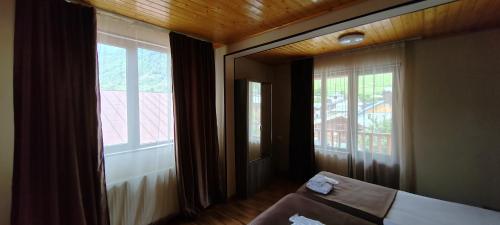 a room with two large windows and a bed in front thereof at Hotel Svanseti in Mestia