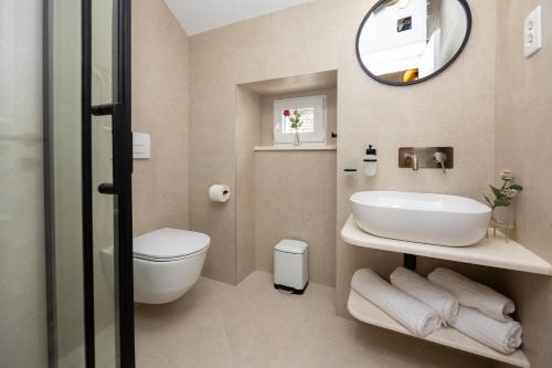 a bathroom with a sink and a toilet and a mirror at Kruna apartments est 2024 in Split