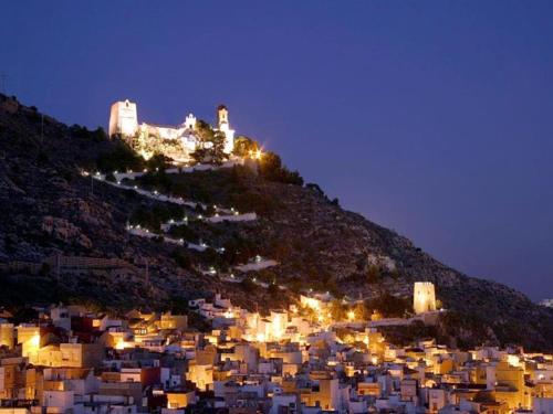 a city lit up at night with a castle on a hill at Amazing beach apartment in Cullera