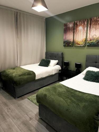 two beds in a room with green walls at Stylish Madison Apartment with Balcony - FREE Car Parking - Hemel Hempstead Town Centre in Hemel Hempstead