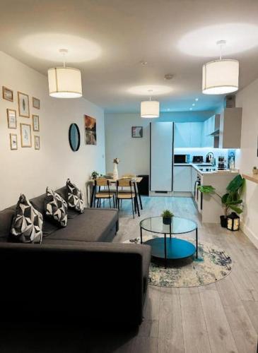 a living room with a couch and a kitchen at Stylish Madison Apartment with Balcony - FREE Car Parking - Hemel Hempstead Town Centre in Hemel Hempstead