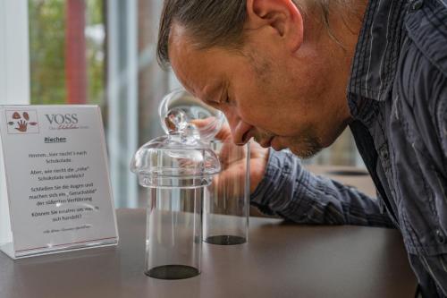 a man is looking at a glass object on a table at Das Schokoladenhotel in Westerstede