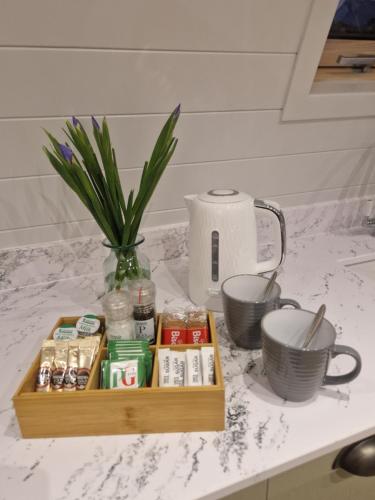 Una bandeja de madera con medicamentos y un jarrón sobre un mostrador. en Bromach Lodge, en Latheron