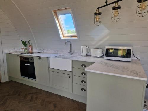 a white kitchen with a sink and a microwave at Bromach Lodge in Latheron
