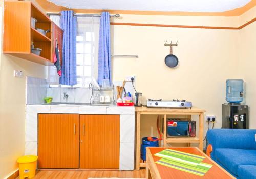 a living room with a kitchen and a blue couch at Shalom Apartments Naivasha in Naivasha