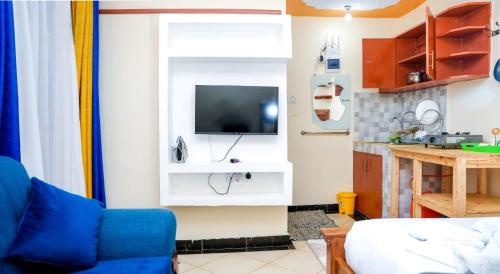 a living room with a blue couch and a tv on a wall at Shalom Apartments Naivasha in Naivasha