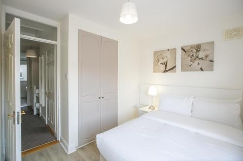 a white bedroom with a white bed and a closet at Grand Canal District Apartments in Dublin