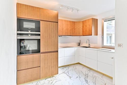 une cuisine avec des armoires blanches, un évier et un micro-ondes dans l'établissement Appartement Spacieux avec Balcon Le Bon marché, à Paris