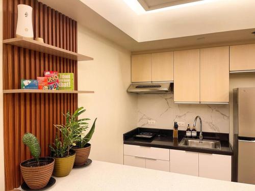 a kitchen with white cabinets and potted plants at Cozy Studio Unit in Abreeza Place Tower 1 with parking in Davao City