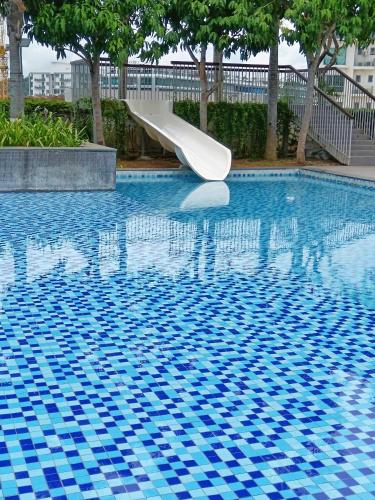 a slide in a swimming pool with blue tiles at Ezyhouz - IMAGO The Loft in Kota Kinabalu