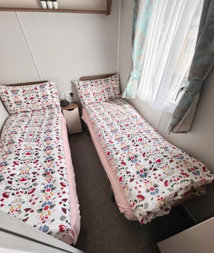 a small bedroom with a bed with a floral comforter at Lovely 3 bedroom holiday home in Seton Sand caravan park Wi-Fi Xbox in Edinburgh