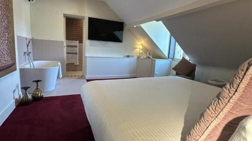 a bedroom with a bed and a bathroom with a tub at Domaine De La Corniche in Rolleboise