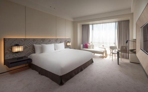 a hotel room with a large white bed and a desk at Crowne Plaza Tainan by IHG in Tainan
