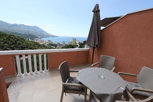 a balcony with an umbrella and a table and chairs at Apartmani Amra in Ivanovići