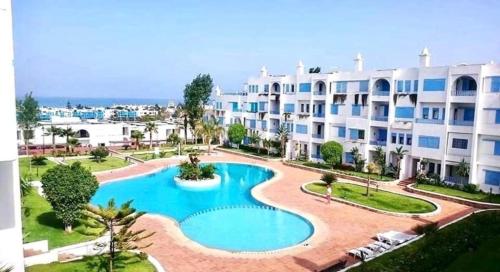 an apartment complex with a swimming pool in front of a building at Appartement Kabila Vista à 10min à pied de la plage in Marina Smir