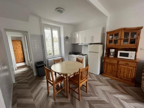 une cuisine avec une table et des chaises dans une pièce dans l'établissement Altitude Location Montagne Appartement 45, à La Bourboule