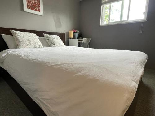 a bed with white sheets and pillows in a bedroom at private room with queen bed in richmond 202 in Richmond