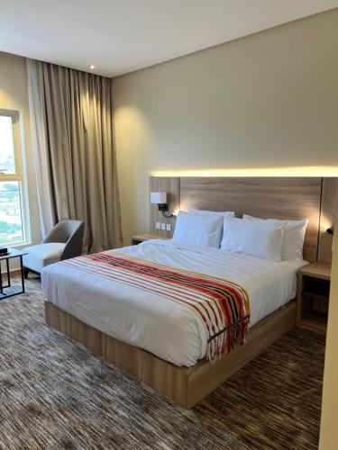 a hotel room with a large bed and a chair at فندق دبليو سويتس - سما أبها in Abha