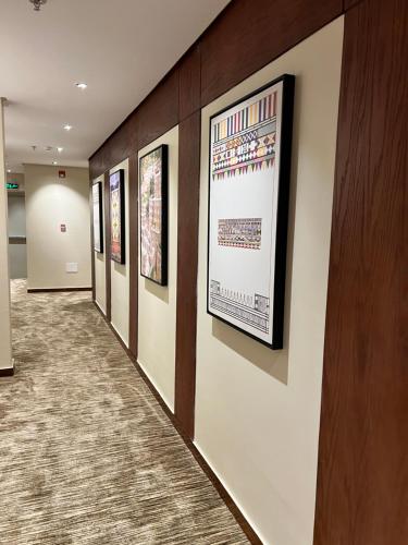 a hallway with a row of framed pictures on a wall at فندق دبليو سويتس - سما أبها in Abha