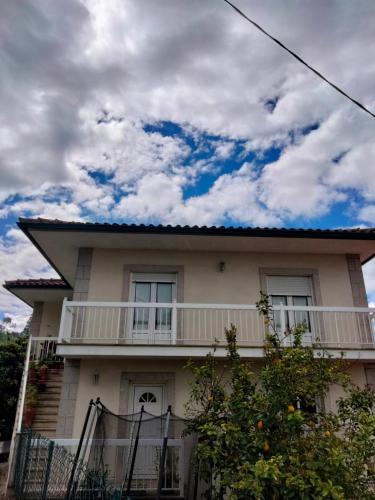 a white house with a balcony and a cloudy sky at La Casa de Marta in Ribeira de Pena