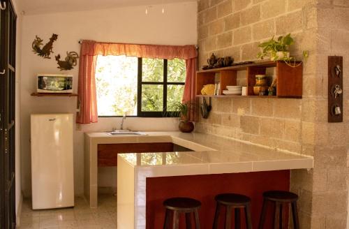 a kitchen with a counter with stools and a sink at El Prado- Casa Maya y Casa Rancho-10 personas in Hoctún