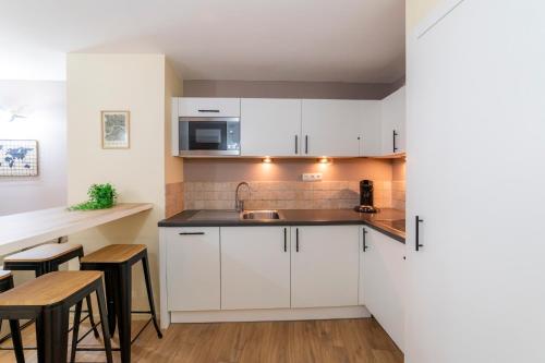 - une cuisine avec des placards blancs, un évier et une table dans l'établissement T2 au cœur du centre historique de Briançon #5, à Briançon