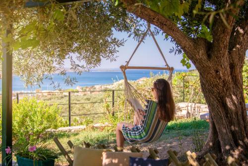a woman sitting in a hammock under a tree at Liodentro - Olea in Plataria