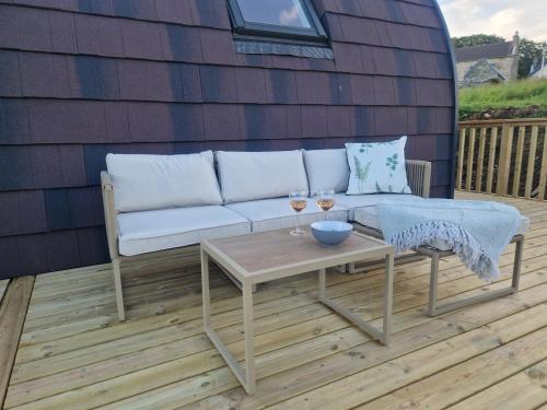 a couch and a table on a deck with wine glasses at Bromach Lodge in Latheron