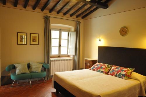 a bedroom with a bed and a chair and a window at Villa Gagnoni in Sinalunga