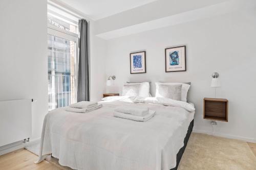 a white bedroom with a large white bed with towels on it at Amazing 2BR w Balcony in the Heart of Aarhus City in Aarhus