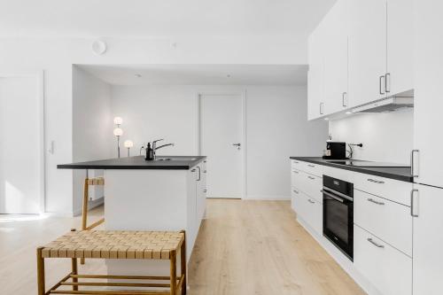 a kitchen with white cabinets and a table and a stool at Amazing 2BR w Balcony in the Heart of Aarhus City in Aarhus