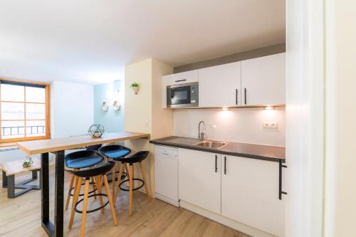 une cuisine avec des placards blancs, une table et des tabourets dans l'établissement T2 au cœur du centre historique de Briançon #3, à Briançon